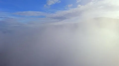 Aerial drone shot of clouds sweeping over the mountains in the golden light Stock Footage 335561712