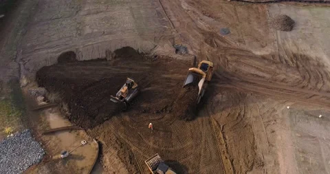 Aerial drone shot of construction worker in a hardhat surrounded by machinery Stock Footage 150220694