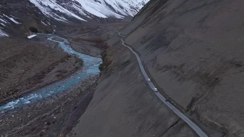 Aerial drone shot displaying a dynamic contrast of landscapes in Spiti, as a car Stock Footage 304951093