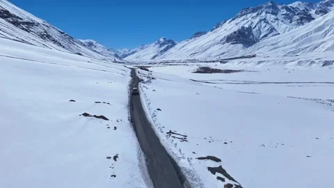 Aerial drone shot displaying a mesmerizing winter journey as a white car moves Stock-Footage 304956083