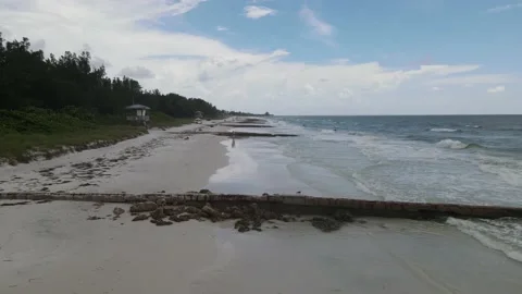 Aerial drone shot down a beach with jettys and people enjoying the crashing w Stock Footage 138518207