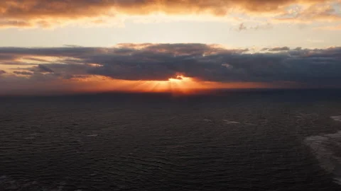 Aerial drone shot of dramatic ocean sunset with sun rays through clouds Stock Footage 325695502