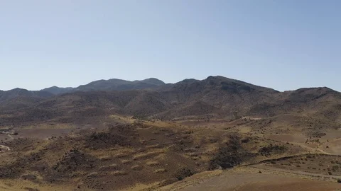 Aerial Drone shot of dry empty spanish desert with vegetation and mountains in Видео 119351051