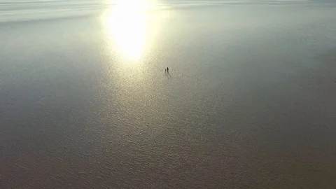 Aerial drone shot elevator shot as a silhouette couple walk on the beach Video stock 124300727