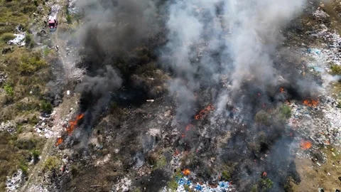 Aerial drone shot of a fire devastating an illegal trash dump next to a big city Stock Footage 253781642