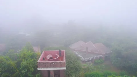 Aerial drone shot flying over man standing on a red brick stone tower looking Stock Footage 331263200