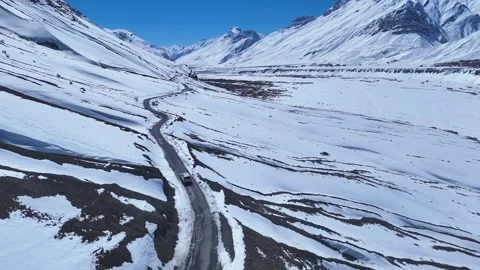 Aerial drone shot following a white car through the serene winter wonderland of Stock Footage 304956341