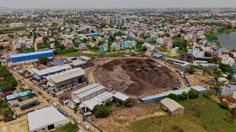 Aerial drone shot of garbage dump yard surrounded by industrial buildings in 動画素材 343830811