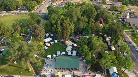 Aerial drone shot looking down at tents set up in small town park for festival Video stock 231511294