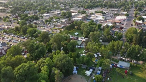 Aerial drone shot looking down at tents set up in small town park for festival Stock Footage 231511454