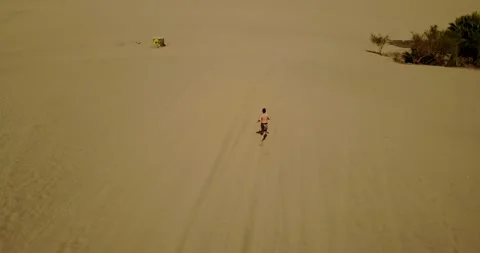 Aerial Drone Shot Of a Man Running on Huacachina, Peru 4K Stock Footage 136178564