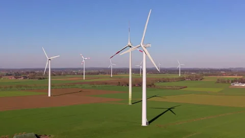 An aerial drone shot of modern wind turbines standing in green agricultural Stock Footage 336407229