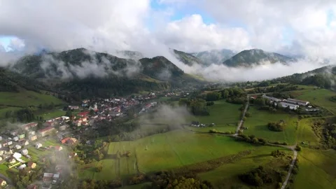 Aerial drone shot moving forward over mountain village and valley with drifting Stock Footage 319828229
