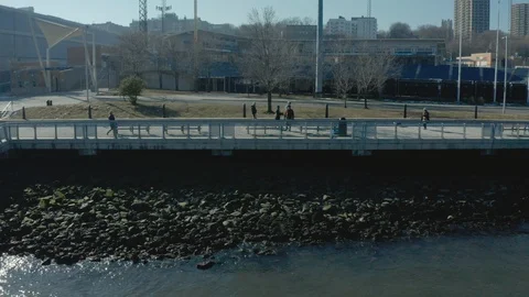Aerial Drone Shot Moving Parallel to Waterfront Promenade with People Walking Stock Footage 122181482