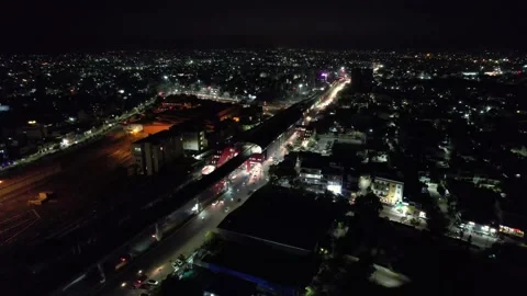 Aerial drone shot at night orbiting elevated metro station with train and a busy Stock Footage 169660966
