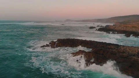Aerial drone shot of ocean waves with pink sky sunrise Stock Footage 261705967