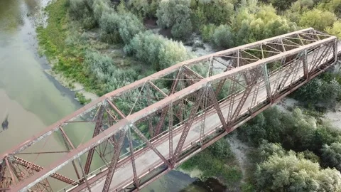 Aerial drone shot of old rusty iron disused railway bridge over the river. Video stock 150363074
