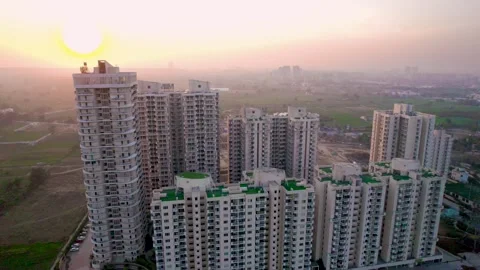 Aerial drone shot orbiting multi story sky scrapers at sunset with green grass Stock Footage 309447731