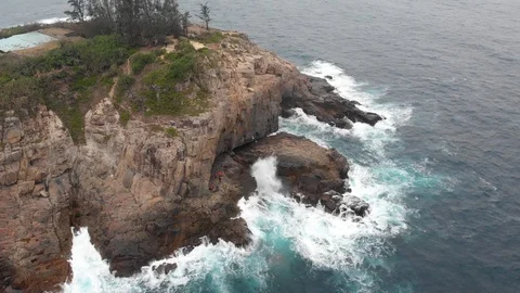 Aerial drone shot panning down to storm waves in the ocean. Rocky coastline. Stock Footage 108523643