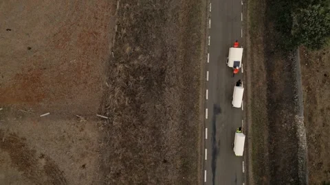 Aerial drone shot of people pulling camping carts on asphalt road amidst ag.. Stock Footage 260389847