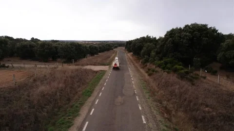 Aerial drone shot of people pulling camping carts on asphalt road amidst ag.. Stock Footage 260389863