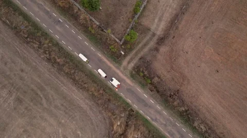 Aerial drone shot of people pulling camping carts on asphalt road amidst ag.. Stock Footage 260389889