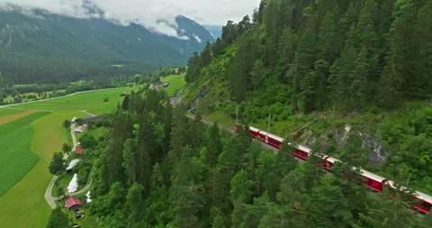 Aerial drone shot red train passing through famous mountain in Filisur Stock-Footage 302079542