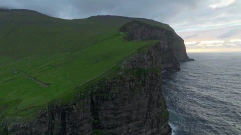 Aerial drone shot of a remote ocean cliff on the Faroe Islands at sunset Stock Footage 337781112