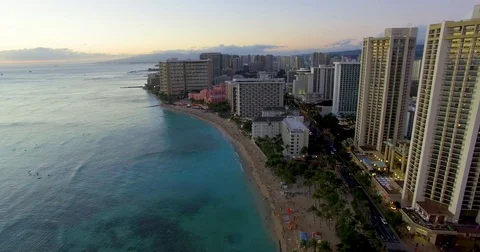 Aerial drone shot rising above a shoreline at sunset Stock Footage
