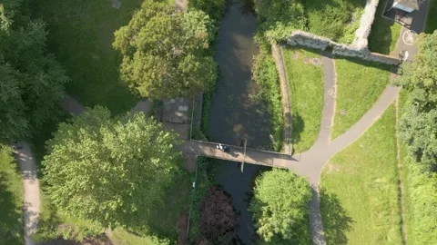 Aerial Drone Shot tilting down over river bridge with grass, trees, picnic Stock Footage 242374305