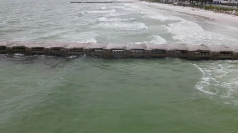 Aerial drone shot tracking ocean waves against a concrete life guard dock Stock Footage 138745193