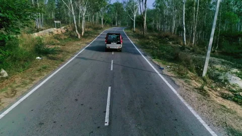 Aerial Drone Shot of Van Moving on Rural Road Through Forest in Mandya 库存影片 334832798