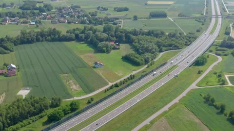 Aerial drone shut of a multilane motorway through green farmland and villages Stock Footage 312593248