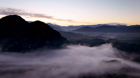 Aerial Drone Side View of Mountain Peak Above Sea of Clouds  at Golden Sunrise Vidéo 335609350