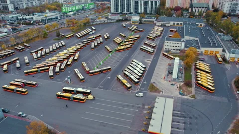 Aerial drone slow motion view of bus depot filled with parked busses. Public Stock Footage 221373537