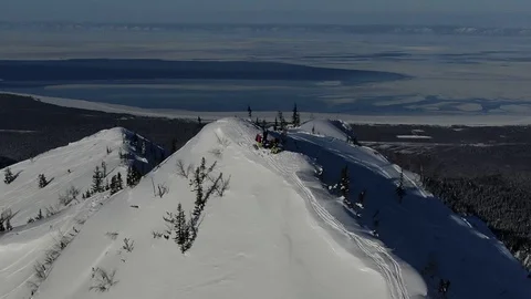 Aerial from drone team freeriders preparing in the snowy mountains uphill in a Stock Footage 102256301