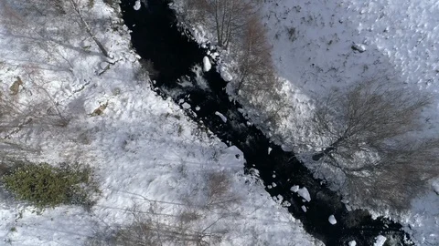 AERIAL DRONE TOP DOWN CLOSE SHOT FROZEN RIVER AND SNOWED FIELDS AND FOREST Stock Footage 130133579