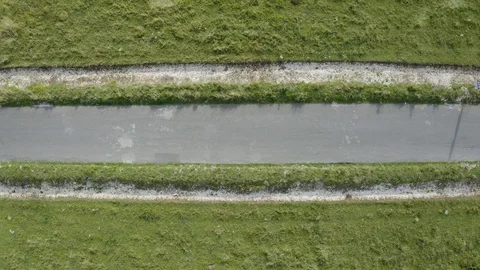 Aerial drone top down shot of three cyclists on a country road Stock Footage 128014083