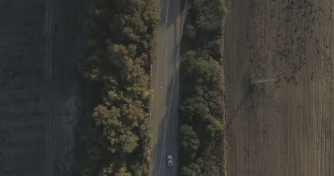 Aerial drone top down tracking shot on a white sport car cruising countryside. Stock Footage 100007045