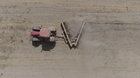 AERIAL DRONE TOP DOWN TRACTOR PLOWING IN ARID AGRICULTURE FIELD WITH DUST Stock Footage 130338952