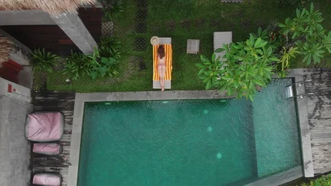 Aerial Drone top down view of slim young woman in beige bikini relaxing and get Stock Footage 128241799