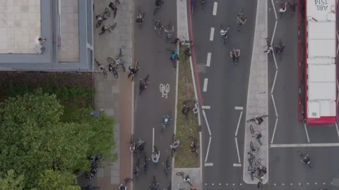 Aerial drone top down view over a road busy with lots of cyclists and cars Stock Footage 148671632