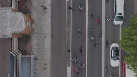 Aerial drone top down view over a road busy with lots of cyclists and cars Stock Footage 148673003