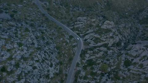 Aerial drone top down view following a car traveling on a winding road Stockbeeldmateriaal 254533947