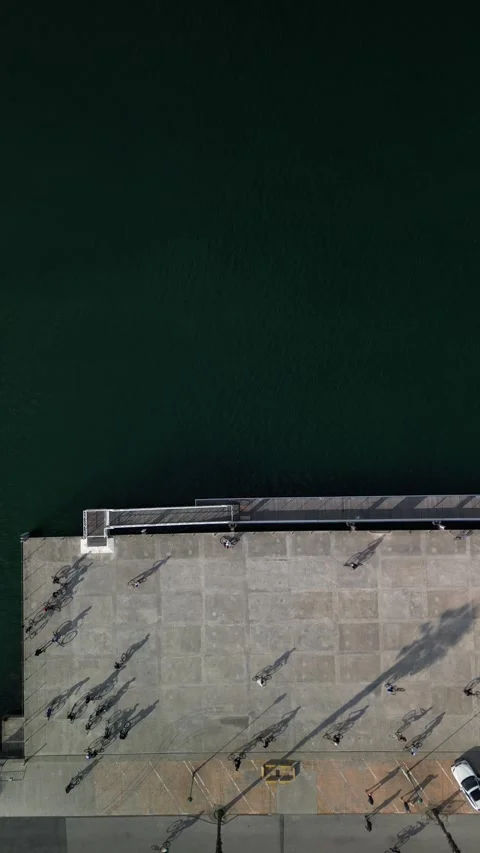 Aerial drone top down view of a group of teenagers cycling next to a pier Stock Footage 274907307
