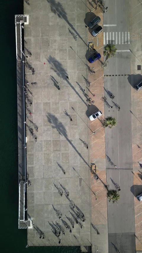 Aerial drone top down view of a group of teenagers cycling next to a pier Stock Footage 274907343