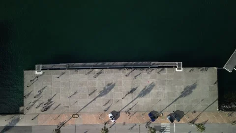 Aerial drone top down view of a group of teenagers cycling next to a pier Stock Footage 274907379