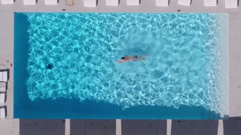 Aerial drone top down view of a person doing freestyle on a serene swimming pool Stock Footage 288457698
