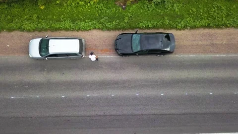 Aerial drone top view of driver attaches tow rope to friend's car near the road Stock Footage 220680735