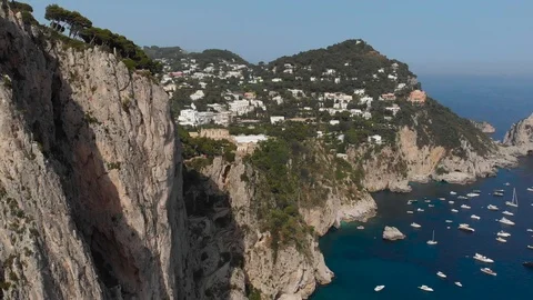 Aerial drone track forward from cliffs and boats in sea to buildings of Capri Video stock 113700746